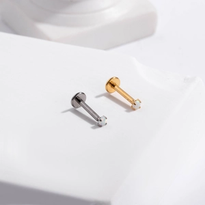 Macro detail of opal stone push-pin labrets in silver and gold titanium finish