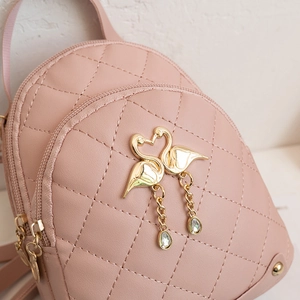 Pink quilted PU backpack featuring a gold twin swan pendant and high-quality texture