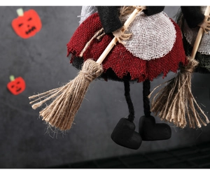 Detail of Halloween witch doll with red burlap dress, white lace apron and straw broom