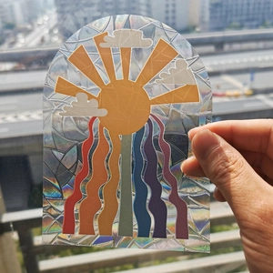Detail showing an arched holographic window sticker reflecting rainbow colors on glass