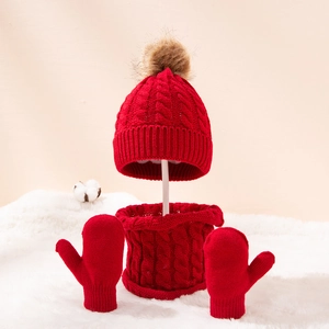 Three-piece red cable knit winter set for kids featuring a pom pom hat, scarf, and mittens