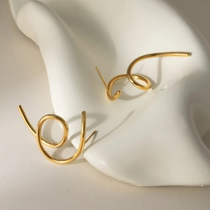 Detailed close-up of golden spiral earrings featuring a polished mirror finish on white stand