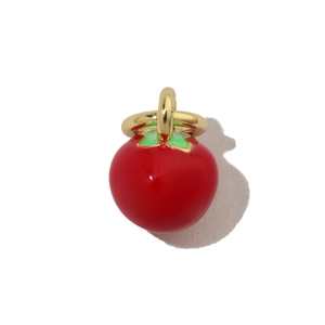 Macro view of a red fruit charm with green leaves and a golden metal loop