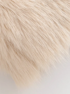 Close-up of soft beige faux fur fabric texture showing dense and smooth plush pile