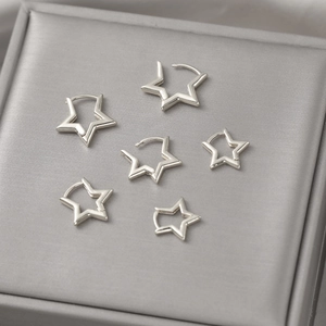 Detailed view of three pairs of silver hollow star-shaped copper hoop earrings in a jewelry box