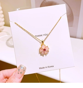 Close-up of pink cherry blossom pendant necklace with cat-eye stone on white jewelry card