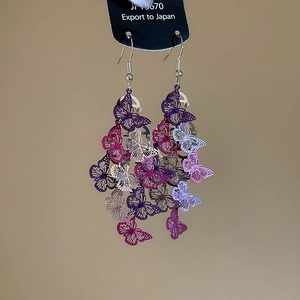 Détail des boucles d'oreilles papillon ajourées avec un dégradé de couleur pourpre