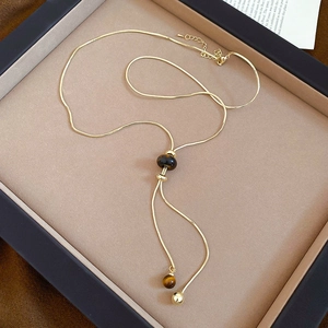 Detail of tiger eye stone pendant on a gold snake chain necklace in a jewelry tray