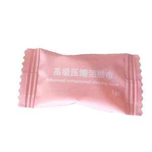 Portable compressed face towel in a pink candy-shaped wrapper for travel hygiene