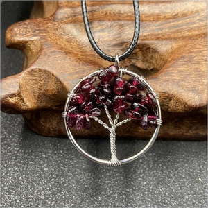 Close-up of tree of life pendant with silver wire wrap and red natural stones