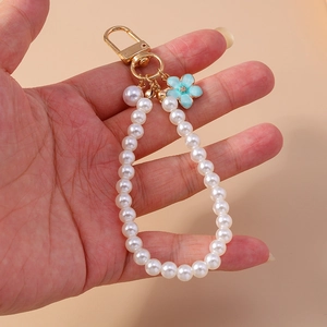 Detail of floral pearl keychain featuring blue enamel flower pendant and gold hardware