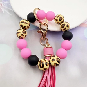 Detail of leopard print wood and silicone bead keychain with pink tassel on white tray