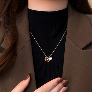 Detail of gold plated necklace with red puppy and heart charm on a model