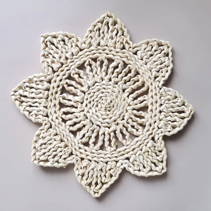 Handwoven natural corn husk table mat in flower shape with clear braided texture