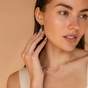 18K gold plated long tassel pearl earrings and necklace set on a model with soft lighting