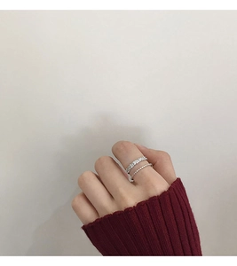 Close-up of stacked silver rings with zircon pavé and twisted band on finger