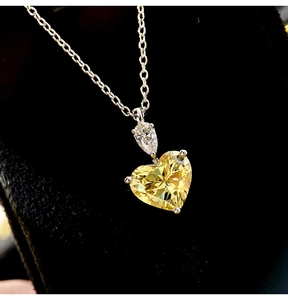 Macro shot showing brilliance of heart-shaped yellow gemstone and silver chain