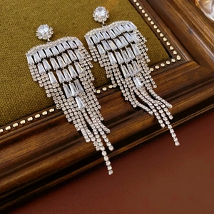 Macro shot of silver tassel earrings with sparkling white zircons on dark velvet