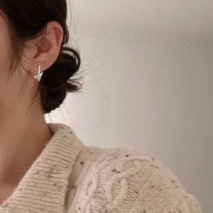 Close-up of minimalist 925 sterling silver knotted hoop earrings on model ear