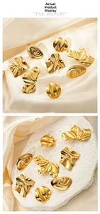 Artistic gold-plated titanium steel earrings displayed on soft satin and stone
