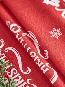 Detail van rode kersttafelloper met Merry Christmas-tekst en sneeuwvlokpatronen
