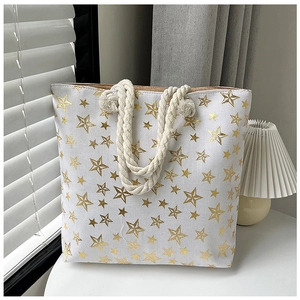 Detail of white canvas tote bag featuring gold foil star print and rope handles