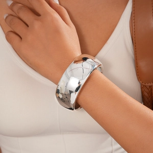 Close-up of a wide polished silver cuff bracelet worn on wrist with mirror finish