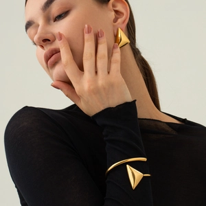 Primo piano degli orecchini a triangolo in acciaio inossidabile dorato 18k e bracciale coordinato