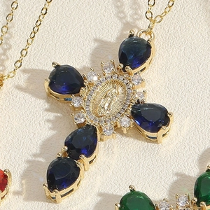 Macro shot of gold cross pendant with blue teardrop stones and Virgin Mary relief