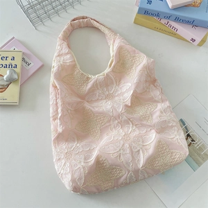 Close-up of pink tote bag featuring delicate white butterfly lace embroidery detail