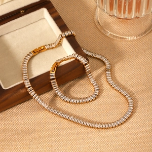 Close-up of gold-plated necklace and bracelet set with emerald-cut zircon inlays