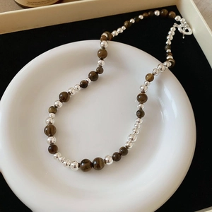 Detailed shot of brown tiger eye stone necklace with silver beads and T-bar clasp