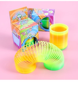 Close-up of vibrant gradient rainbow spring toys with colorful packaging boxes on pink background