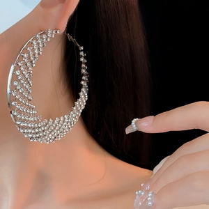 Detailed view of oversized silver hoop earrings with dense rhinestone pavé on a model