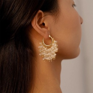 Detail of 18k gold plated hoop earrings with star charms and clustered crystal beads