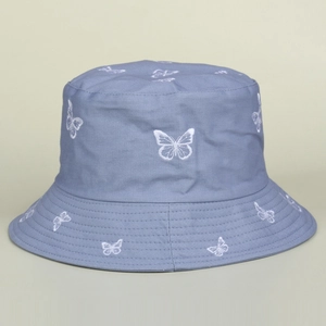 Close-up of white butterfly embroidery detail on blue cotton bucket sun hat fabric