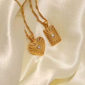 Détail de pendentifs en acier doré 18K avec texture soleil et pierres de zircone