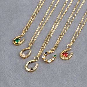 Detailed view of U-shaped gold necklaces with colorful zircon stones on grey fabric