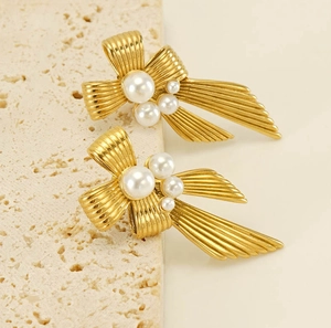 Detail of vintage gold bow earrings with vertical brushed texture and white pearls