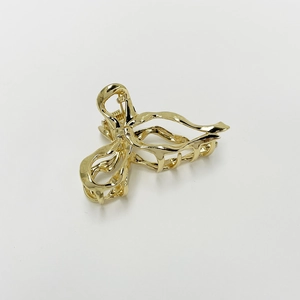 Detailed view of elegant gold metal bow-knot hair claw clip with smooth polished finish