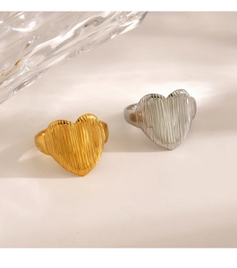 Detail of gold and silver heart rings with vertical striped texture and matte finish