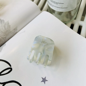 Pince à cheveux élégante en acétate vert jade avec texte doré sur livre blanc