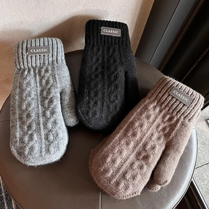 Men's winter knit mittens in grey black and brown with classic labels on a leather stool