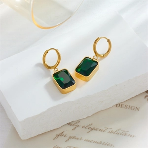 Vintage gold hoop earrings with square green gemstone charms on a marble stone base