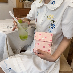 Detail of pink heart-patterned cotton storage bag with a white resin snap closure