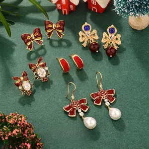 Detail of Christmas bow earrings with wine red enamel and pearls on a festive background