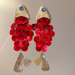 Detailed view of handmade fish-shaped earrings with red sequins and blue evil eye charms