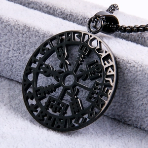 Black Viking compass pendant necklace with Nordic runes on a textured grey cushion