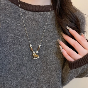 Detailed view of rocking horse pendant with pearls on a dark grey sweater