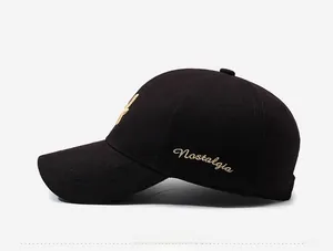 Detail view of gold Nostalgia embroidery on black cotton twill baseball cap side